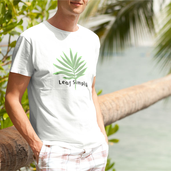 Man wearing Leaf Simply Palm Leaf design White Unisex Cotton T-Shirt next to a palm tree